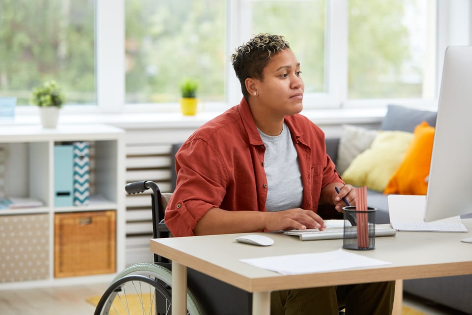 Māori woman in a wheelchair sitting at a desk