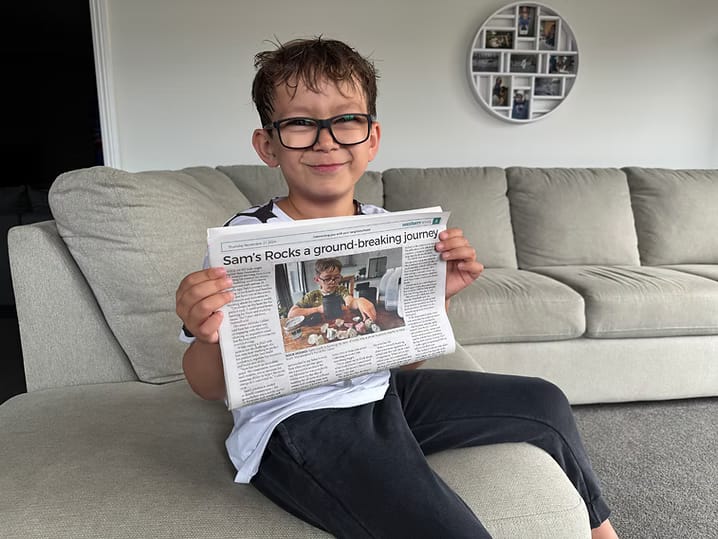 Sam sitting on a couch holding a newspaper