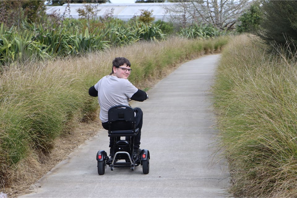 Nathan riding his Nordic Travel Scooter along a path