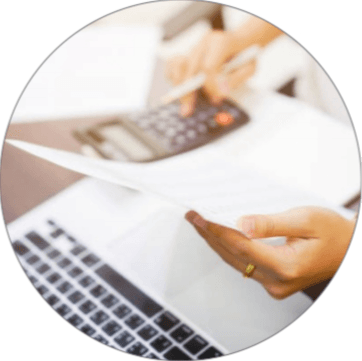 Hands using a calculator next to a laptop